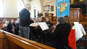 Conductor, clarinets, sax, horns, tuba and a trombone squeezed into the church