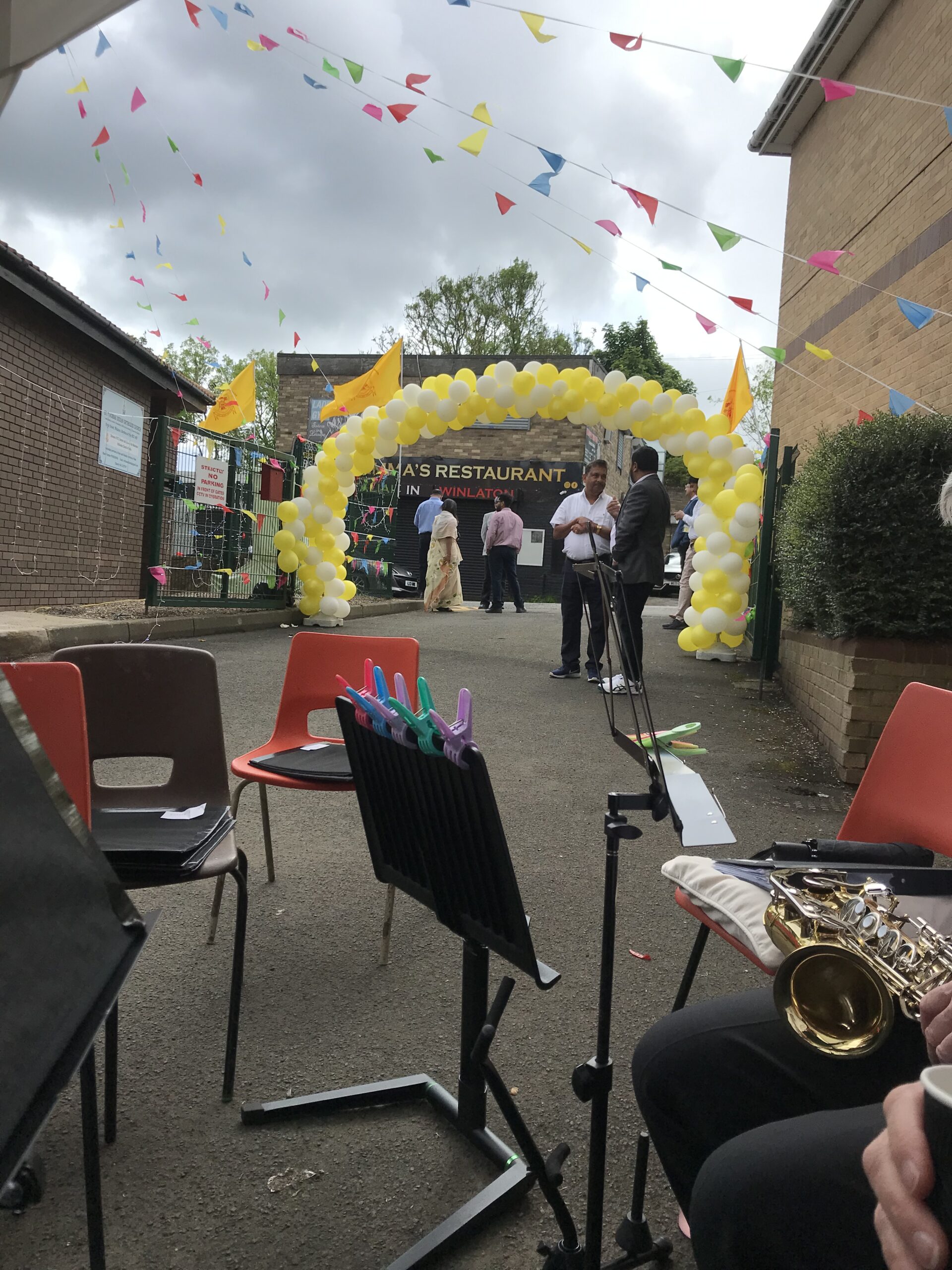 Saxaphone, music stands and chairs framed by giant arch of balloons and bunting.