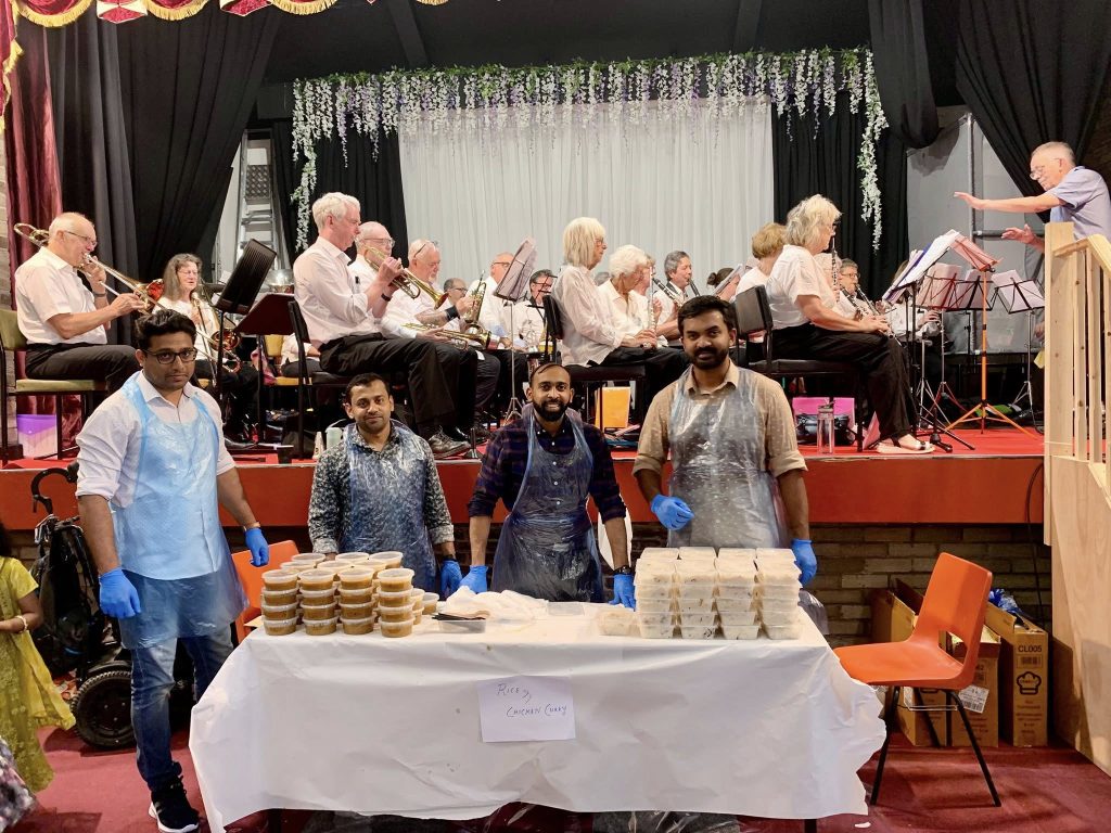 showing curry and rice stall in front of stage with 27 band members
