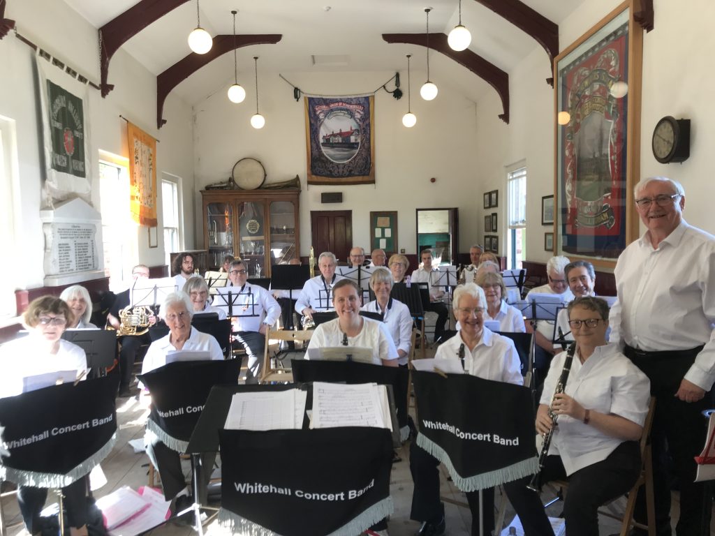 showing musicians with white tops inside the Band Hall. All behind our music stand covers.